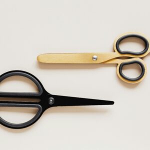 Top view of multicolored scissors of different shape on beige table